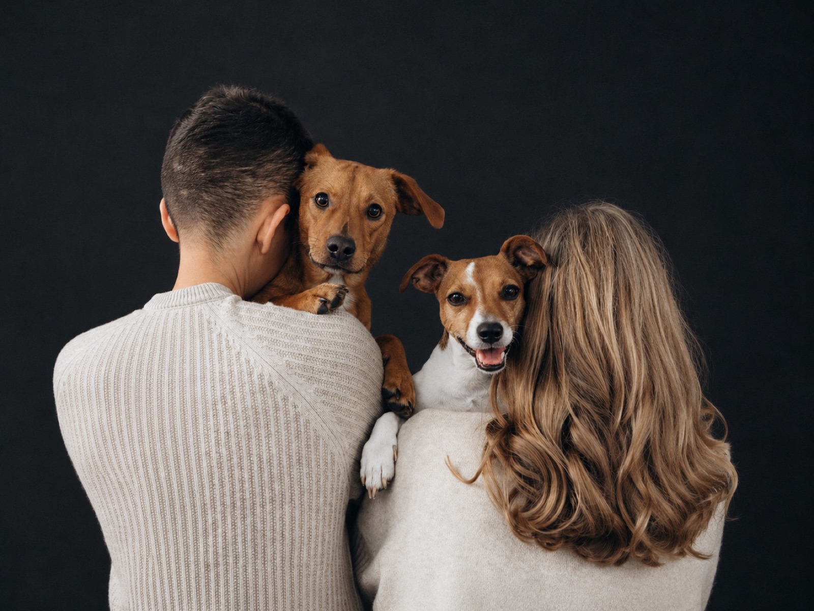 Pareja de espaldas con sus dos perros en brazos
